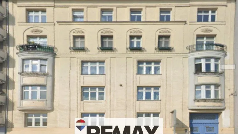 Die Fassade eines Altbaus mit mehreren Fenstern und zwei Erkern mit kleinen Balkonen.