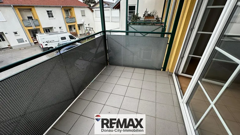 Geräumiger Balkon mit Fliesenboden und Blick auf die umliegenden Gebäude und die Straße.