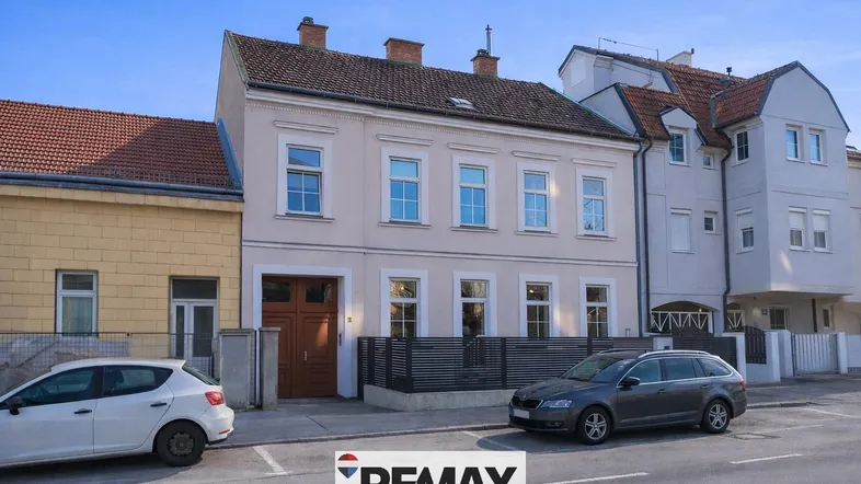 Historisches Gebäude mit heller Fassade und klassischen Fenstern an einer ruhigen Straße.