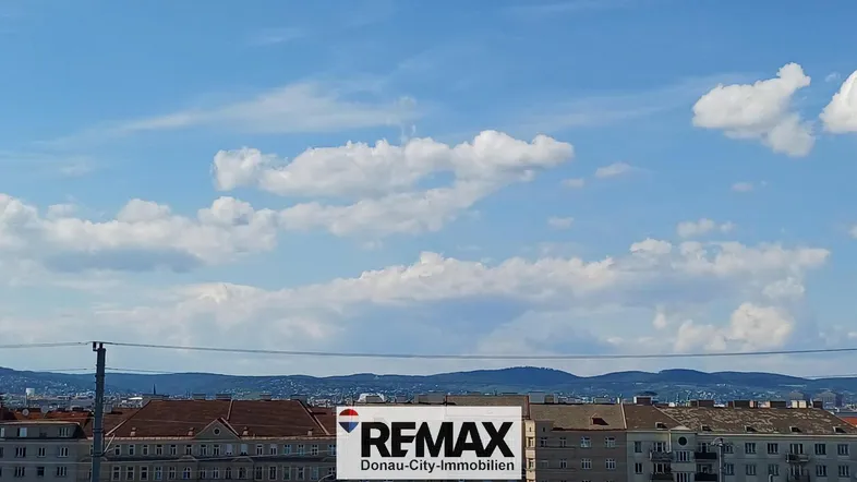 Weitblick über die Stadt mit Bergen im Hintergrund unter blauem Himmel.