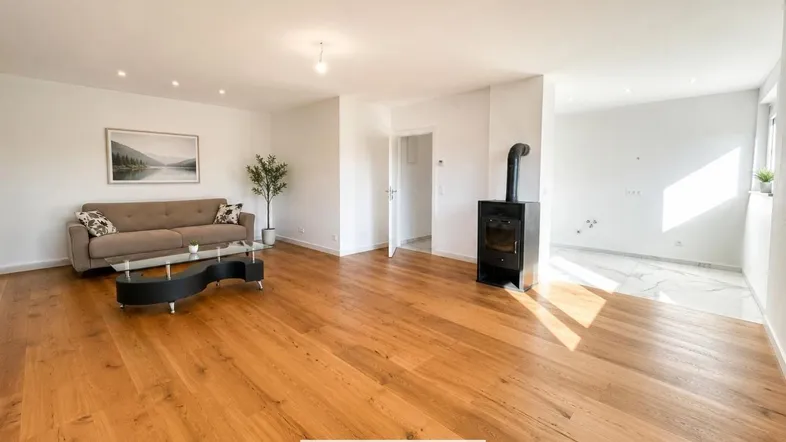 Helles Wohnzimmer mit Holzboden, gemütlichem Sofa und modernem Holzofen als Blickfang.