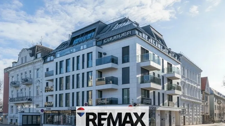 Modernes Gebäude mit Glasbalkonen und markanter Architektur in städtischer Umgebung.