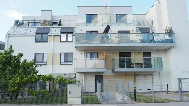 Modernes Mehrfamilienhaus mit Balkonen und Terrassen, umgeben von einer gepflegten Grünanlage.