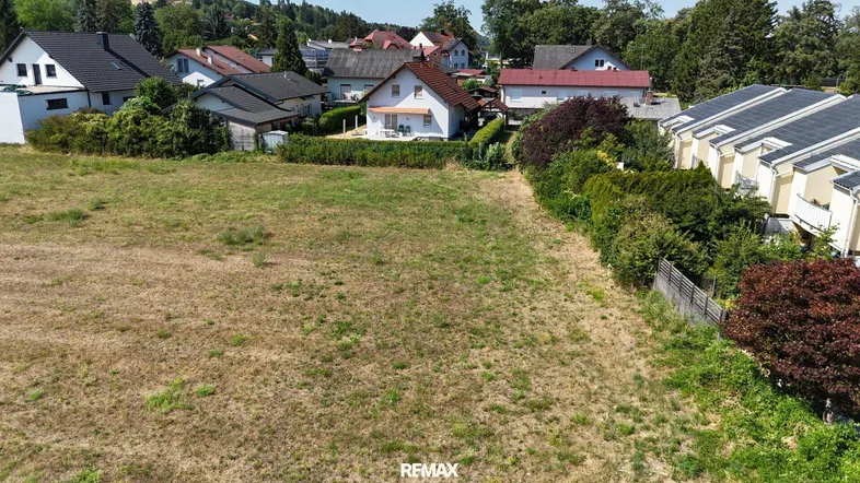 Luftaufnahme eines unbebauten Grundstücks mit angrenzenden Wohnhäusern in ländlicher Umgebung.