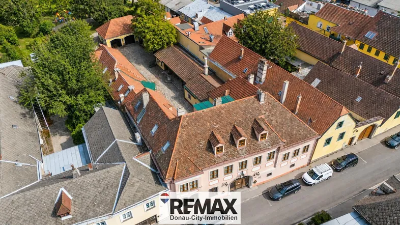 Luftaufnahme eines historischen Gebäudekomplexes mit mehreren Dächern und einem Innenhof.
