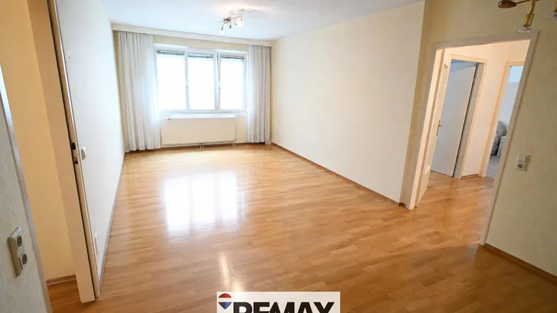 Helles Wohnzimmer mit Parkettboden und großen Fenstern, bereit zur individuellen Gestaltung.