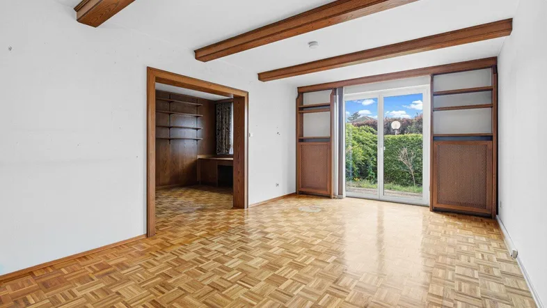 Helles Wohnzimmer mit Fischgrätparkett, Holzbalken und Zugang zum Gartenbereich.