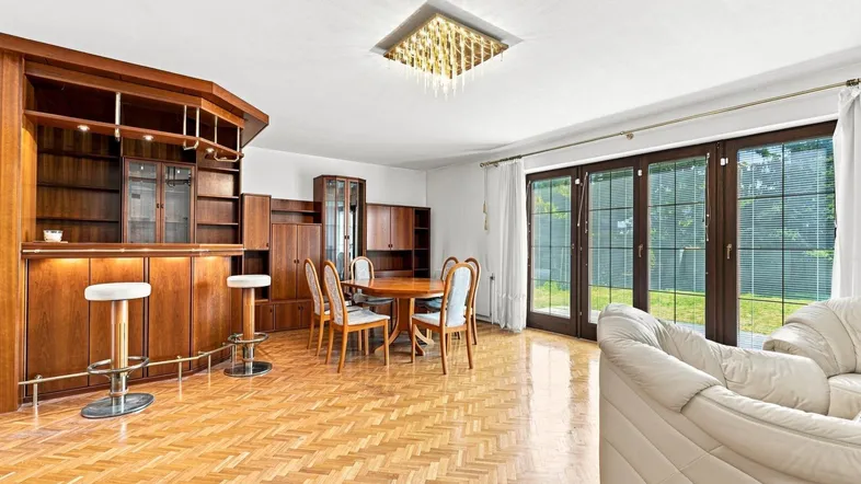 Geräumiger Wohn- und Essbereich mit Holzparkett, integrierter Bar und Zugang zum Garten.