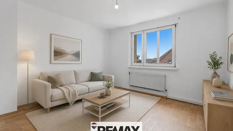 Helles Wohnzimmer mit beigem Sofa, Teppich und Blick aus dem Fenster.