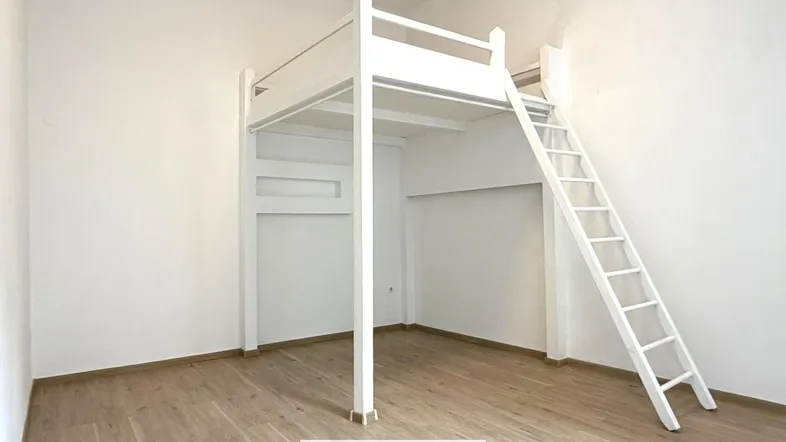 Helles Zimmer mit weißem Hochbett und Holzfußboden, ideal für ein Schlafzimmer.