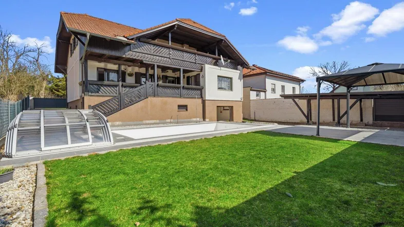 Außenansicht des Hauses mit gepflegtem Garten, Pool und überdachtem Bereich.