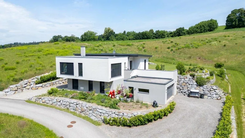 Modernes Einfamilienhaus mit Flachdach und gepflegter Außenanlage in ländlicher Umgebung.