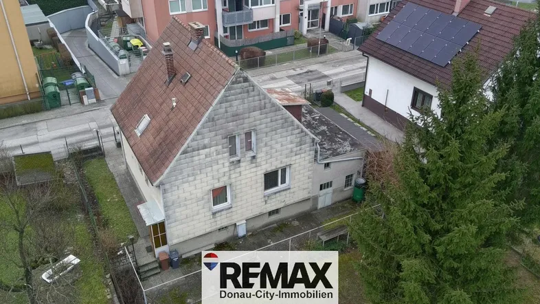 Luftaufnahme eines Einfamilienhauses mit Satteldach und umliegender Bebauung.