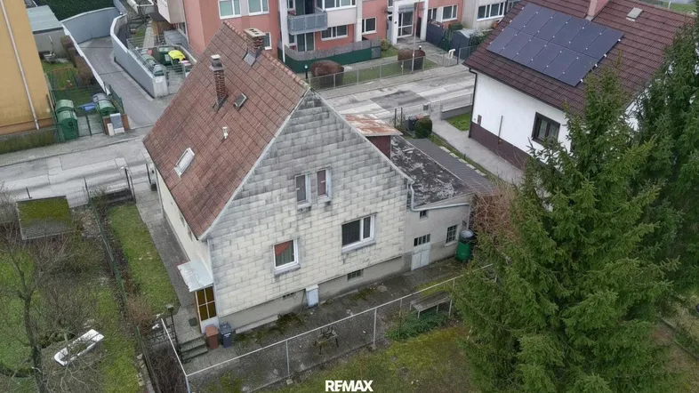 Luftaufnahme eines Einfamilienhauses mit Garten, Satteldach und angrenzenden Gebäuden.