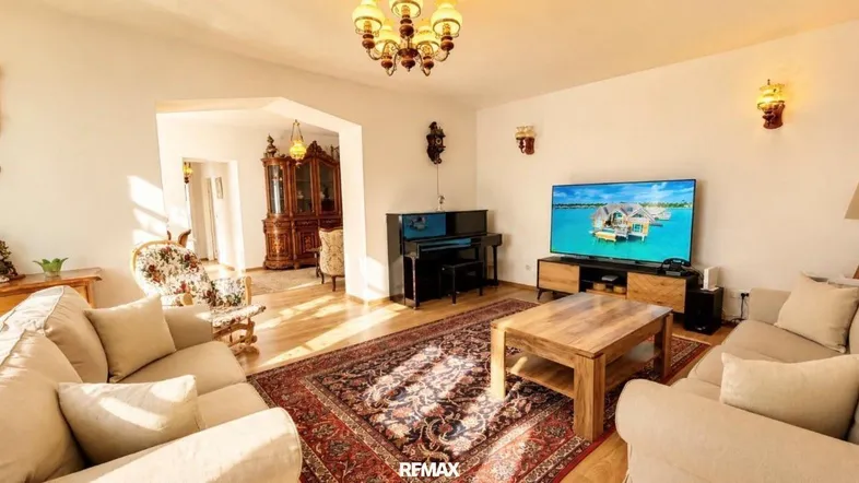 Geräumiges Wohnzimmer mit traditionellen Möbeln, Teppichboden und Fernseher.