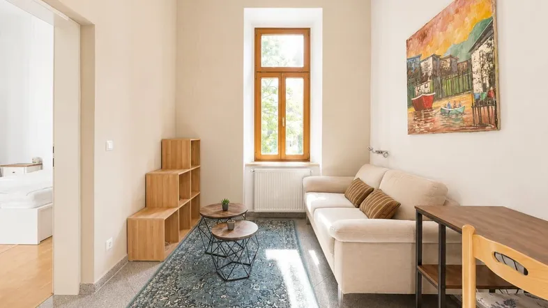 Helles Wohnzimmer mit beigem Sofa, Holzelementen und einem Fenster mit Blick ins Grüne.