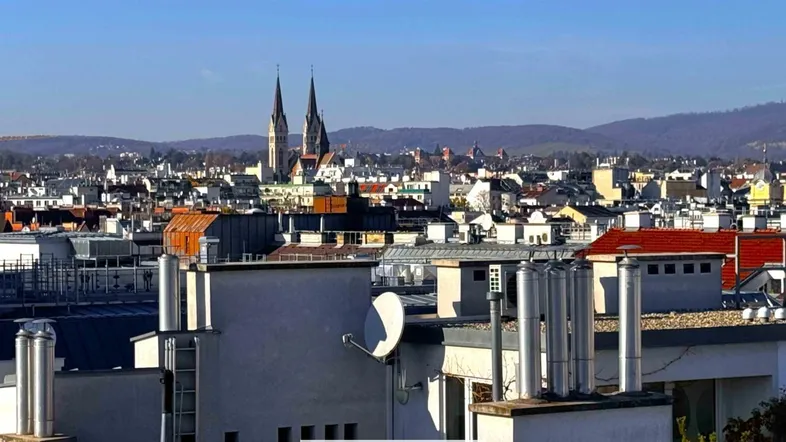 Panoramablick über die Stadt mit historischen Gebäuden und Kirchtürmen im Hintergrund unter blauem Himmel.
