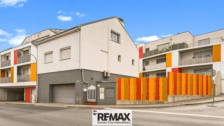 Gebäudeansicht von der Straße mit moderner Fassade und farbigen Akzenten.
