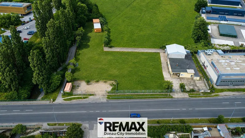 Luftaufnahme eines großen grünen Grundstücks mit angrenzender Straße und umliegenden Gebäuden.