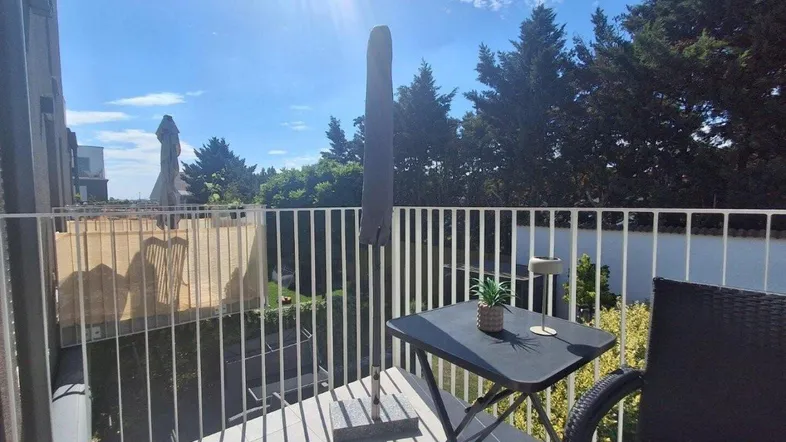Heller Balkon mit Sitzgelegenheiten und Blick ins Grüne, ideal für entspannte Stunden im Freien.