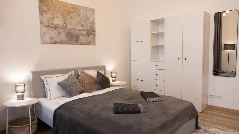 Helles Schlafzimmer mit großem Bett, weißem Kleiderschrank und moderner Dekoration.