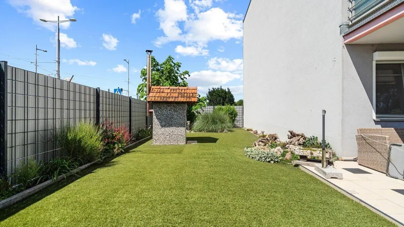 Gepflegter Gartenbereich mit Kunstrasen und einem gemauerten Pizzaofen für gemütliche Abende im Freien.