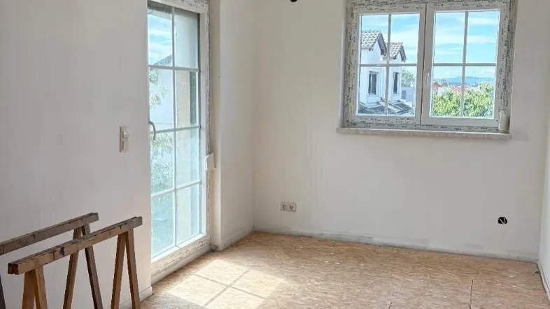 Unfertiger Raum mit OSB-Plattenboden und Fenstern, bereit für den weiteren Ausbau.