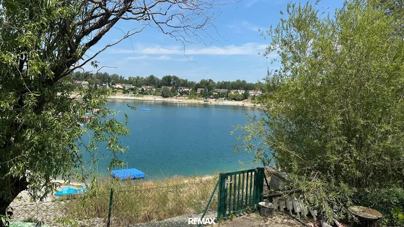 Malerischer Blick auf einen See mit Häusern am Ufer, umgeben von üppigem Grün.