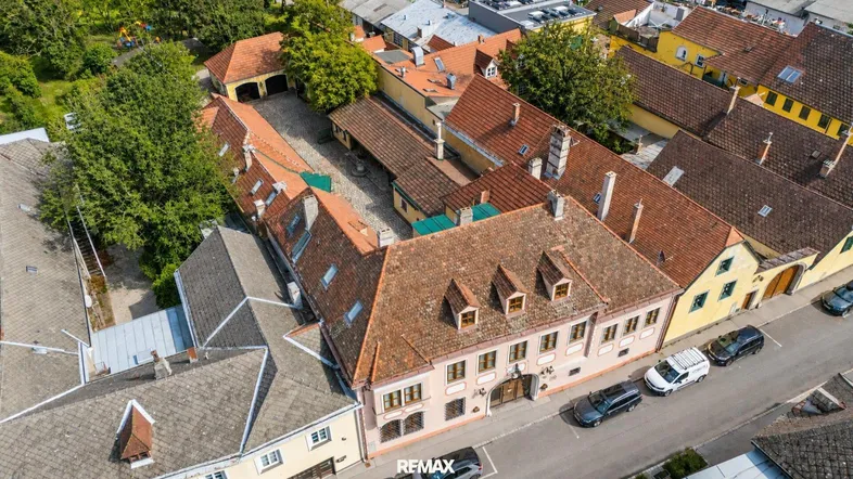 Luftaufnahme des Anwesens mit mehreren Gebäuden und einem Innenhof, umgeben von viel Grün.
