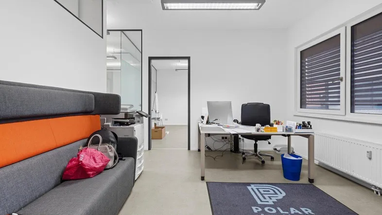 Modernes Büro mit Schreibtisch, Sofa und großen Fenstern, ideal für produktives Arbeiten.