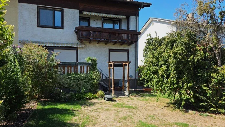 Hinteransicht des Hauses mit Gartenbereich und einem kleinen Balkon im Obergeschoss.