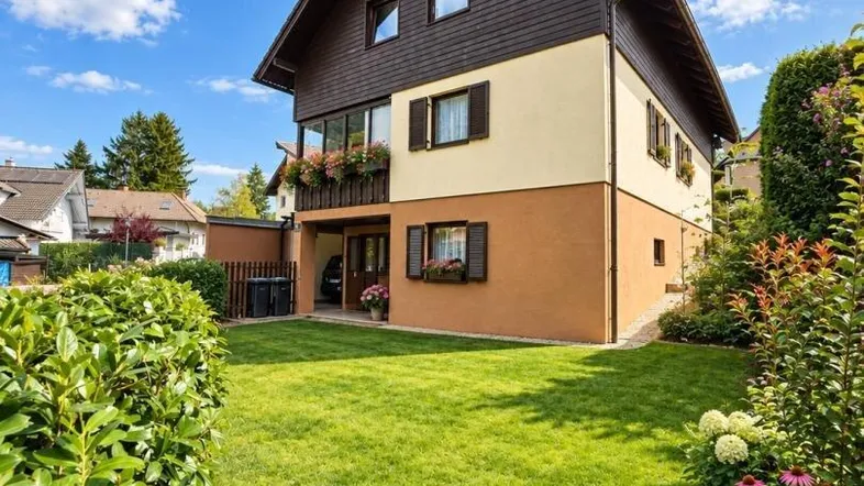 Traditionelles Haus mit gepflegtem Garten und blühenden Pflanzen unter blauem Himmel.