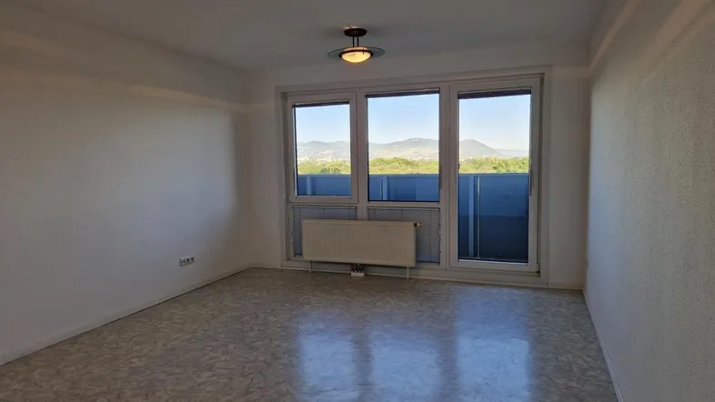 Helles Zimmer mit gemustertem Boden, weißen Wänden und Blick auf die umliegende Landschaft.