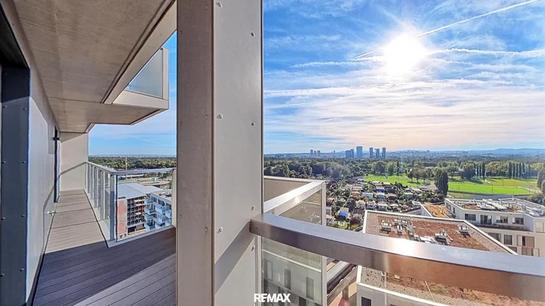 Geräumiger Balkon mit Holzboden und weitem Blick über die Stadt und grüne Landschaften.