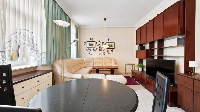 Gemütliches Wohnzimmer mit beigem Sofa, dunklen Holzmöbeln und Teppichboden.