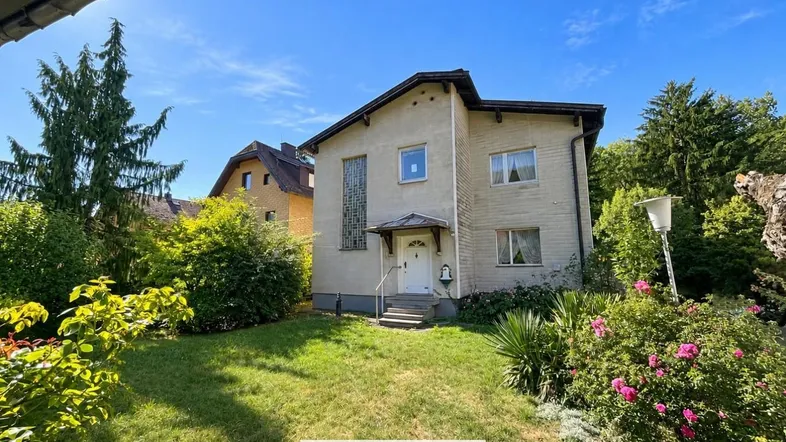 Einfamilienhaus mit gepflegtem Vorgarten und traditioneller Architektur unter blauem Himmel.