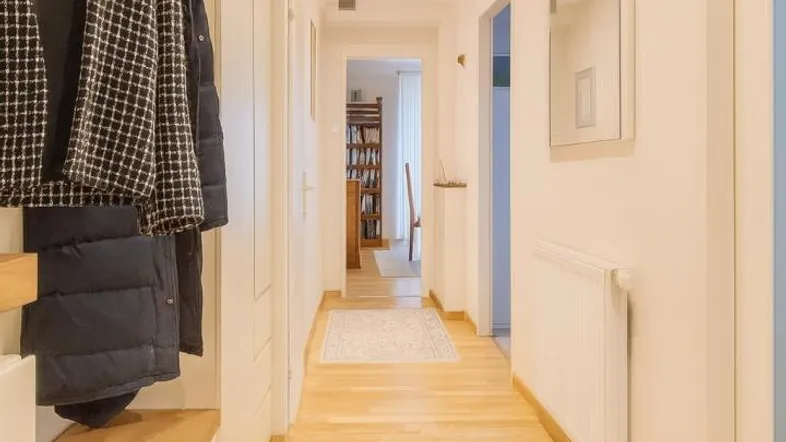 Heller Flur mit Holzfußboden, Garderobe und Einbauschränken, der in weitere Räume führt.