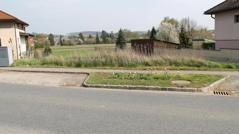 Blick auf ein unbebautes Grundstück mit angrenzender Straße und ländlicher Umgebung.