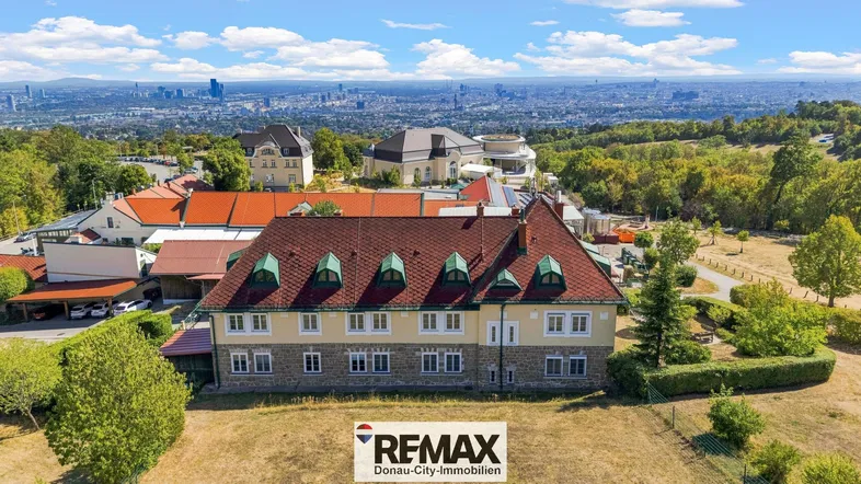 Luftaufnahme eines großen Gebäudekomplexes mit Blick auf die Stadt Wien und die umliegende Landschaft.