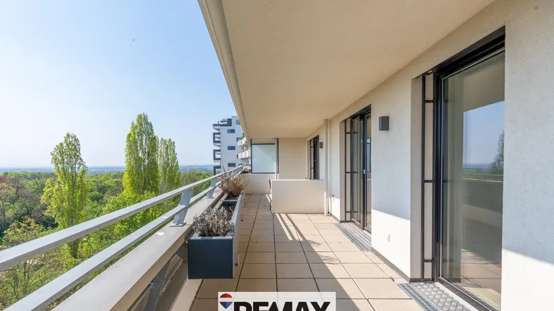 Langer Balkon mit Fliesenboden und weitem Blick ins Grüne und auf die Stadt.