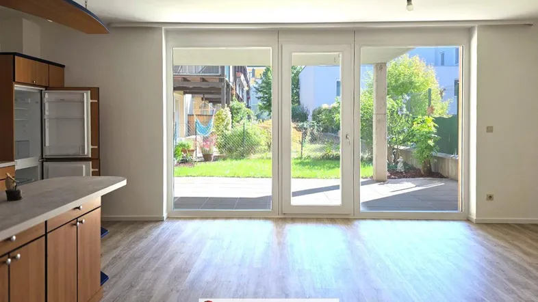 Heller offener Wohnbereich mit integrierter Küche, Laminatboden und Zugang zur Terrasse und zum Garten.