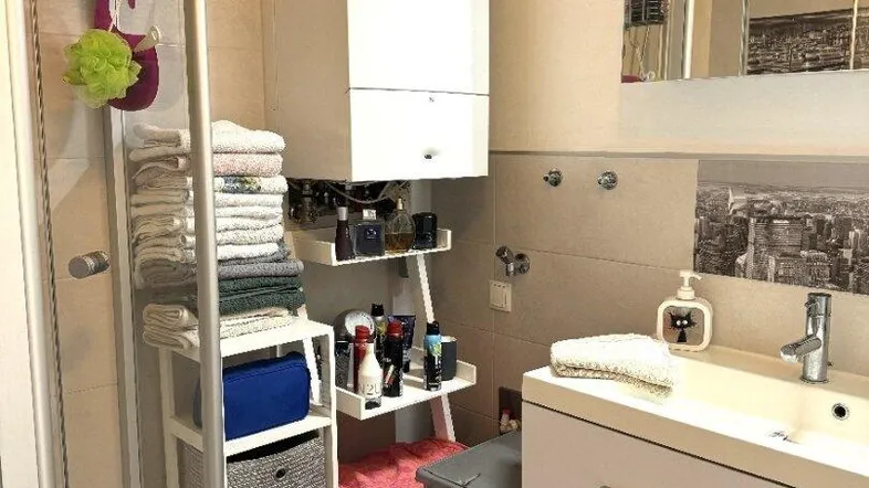 Modernes Badezimmer mit Dusche, Waschbecken und integriertem Warmwasserbereiter, funktional eingerichtet.
