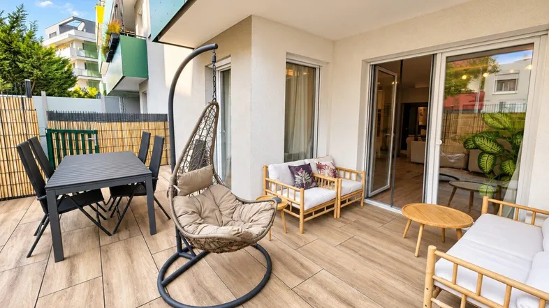 Geräumige Terrasse mit Essbereich, Lounge-Möbeln und Hängesessel, ideal für Entspannung im Freien.