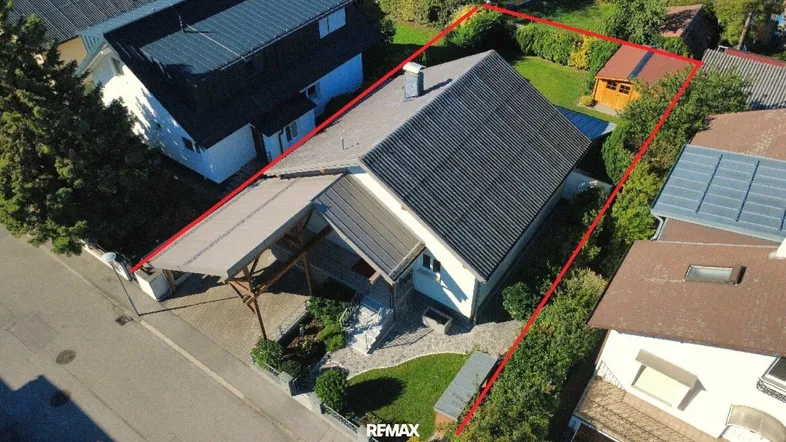 Luftaufnahme eines Einfamilienhauses mit Garten und Carport, umrandet von einer roten Linie.