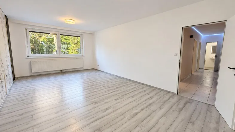 Helles, leeres Zimmer mit Laminatboden und Blick ins Grüne, bereit zur individuellen Gestaltung.