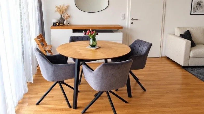 Heller Essbereich mit modernem Holztisch, bequemen Stühlen und Parkettboden, offen zum Wohnbereich.