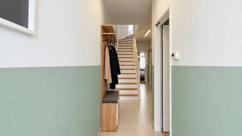 Heller Flur mit Fliesenboden, Garderobe und Blick zur Treppe.