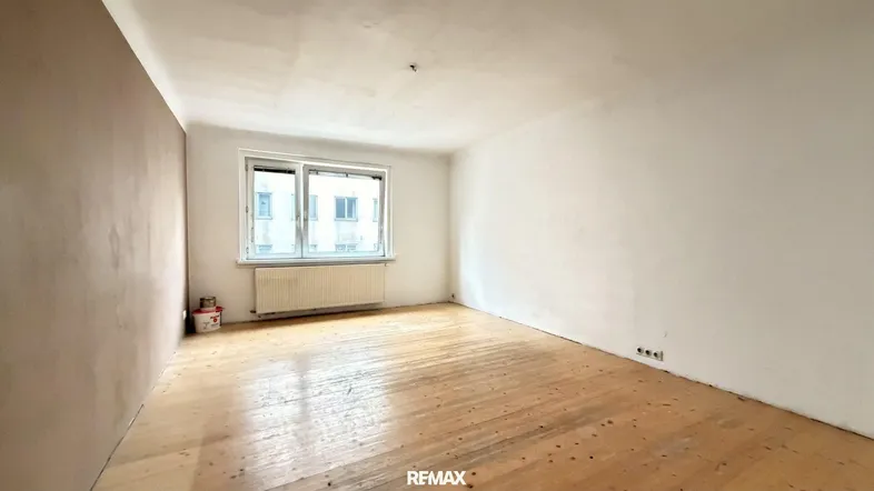 Heller Raum mit Holzdielenboden und einem Fenster, bereit für die individuelle Gestaltung.