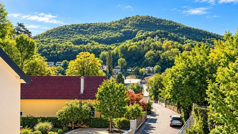 Panoramablick auf eine Wohnsiedlung mit grünen Hügeln und sonniger Umgebung.