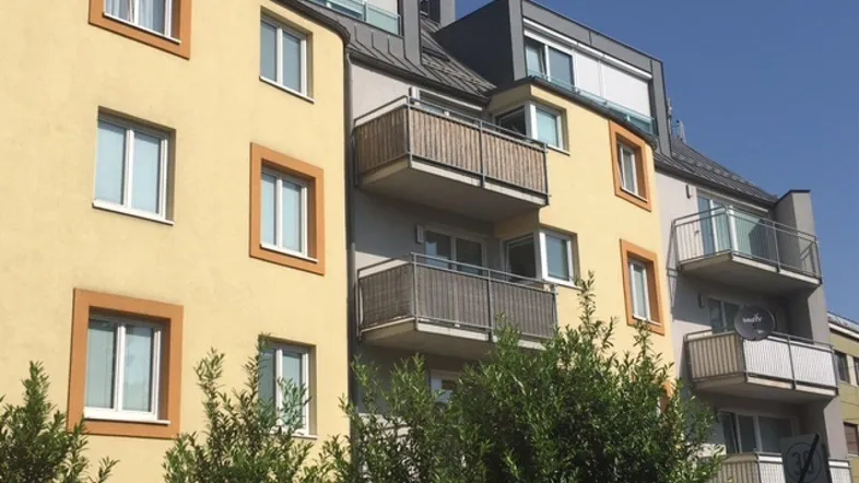 Ansicht der modernen Wohnanlage mit mehreren Balkonen und gelber Fassade.
